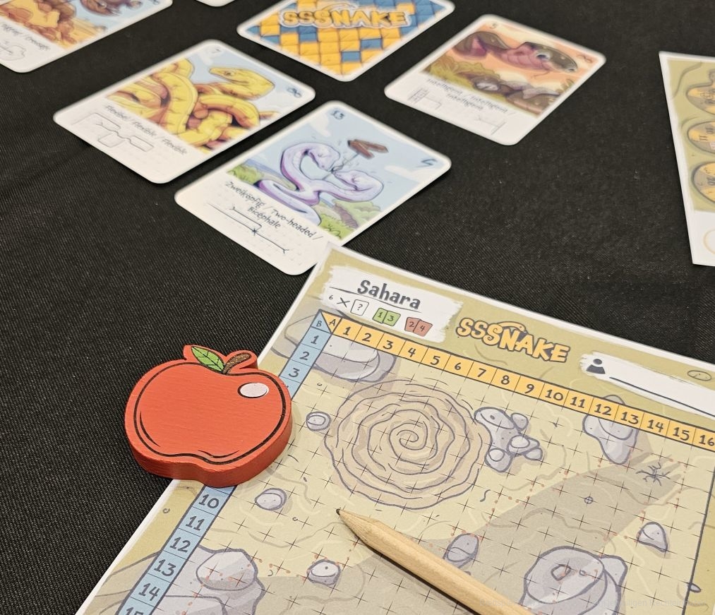 "Sssnake: Flip&Write" ist ein schnell erlerntes, außergewöhnliches Grid-Movement-Flip&Write-Spiel für 2-6 Personen ab 8 Jahren mit einer Spieldauer von 20-30 Minuten, in dem wir uns über abwechslungsreiche Karten schlängeln, die aus verschiedenen Untergründen bestehen. Dabei fressen wir Äpfel, um länger zu werden und Spezialfähigkeiten zu erlernen.